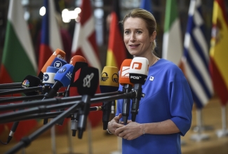 Kaja Kallas sinises kleidis mikrofonide ees, taamal eri riikide lipud